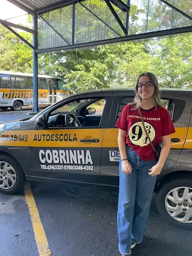 Aluna ao lado do carro da Autoescola Cobrinha